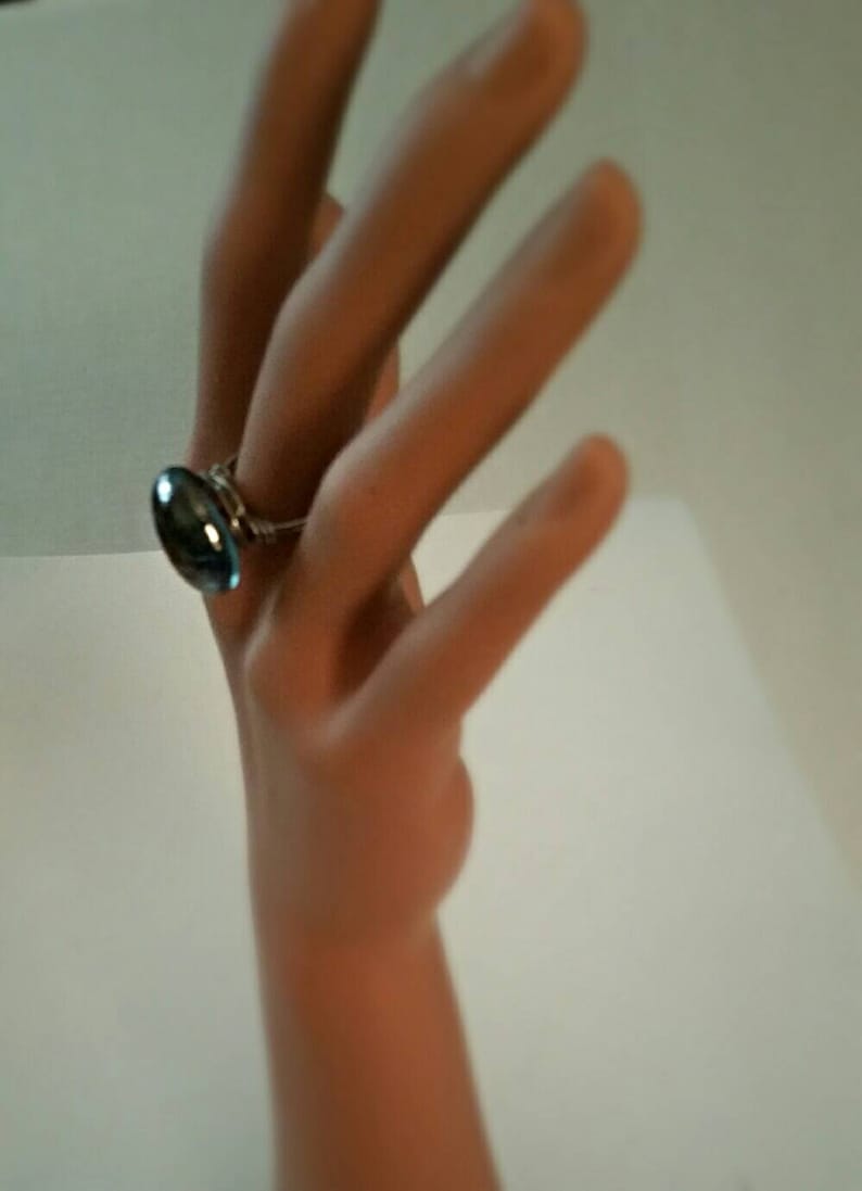Puede incluir: Un anillo de plata con una piedra ovalada azul.