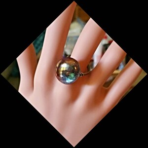 May include: A ring with a large iridescent blue, green, and purple sphere.
