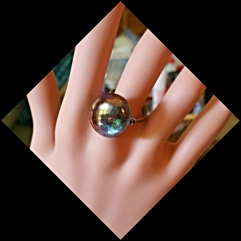 Puede incluir: Un anillo con una gran esfera iridiscente azul, verde y morada.