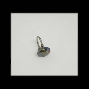 Puede incluir: Un anillo de alambre plateado con una piedra ovalada de color iridiscente oscuro.
