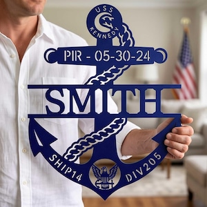 May include: A dark blue metal anchor wall sign featuring the text USS KENNEDY, PIR - 05-30-24, SMITH, SHIP14, and DIV205. The design includes a rope wrapped around the anchor shaft and a central eagle emblem at the base of the anchor fluke.