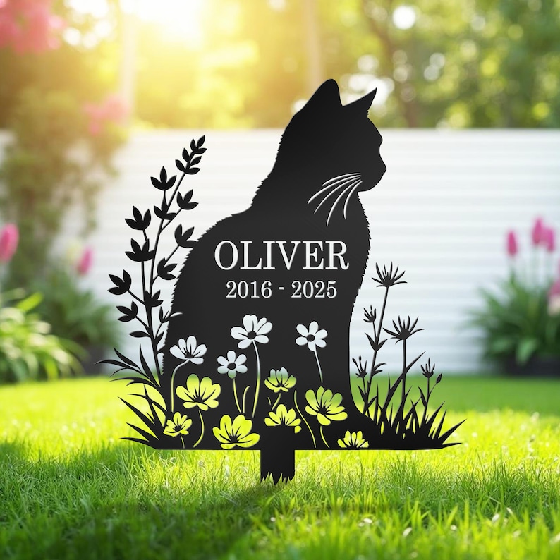 Puede incluir: Estaca de jard&iacute;n de metal negro con silueta de gato con el nombre "OLIVER" y las fechas "2016-2025". El gato est&aacute; rodeado de recortes florales y vegetales. La estaca est&aacute; dise&ntilde;ada para colocarse en un jard&iacute;n.