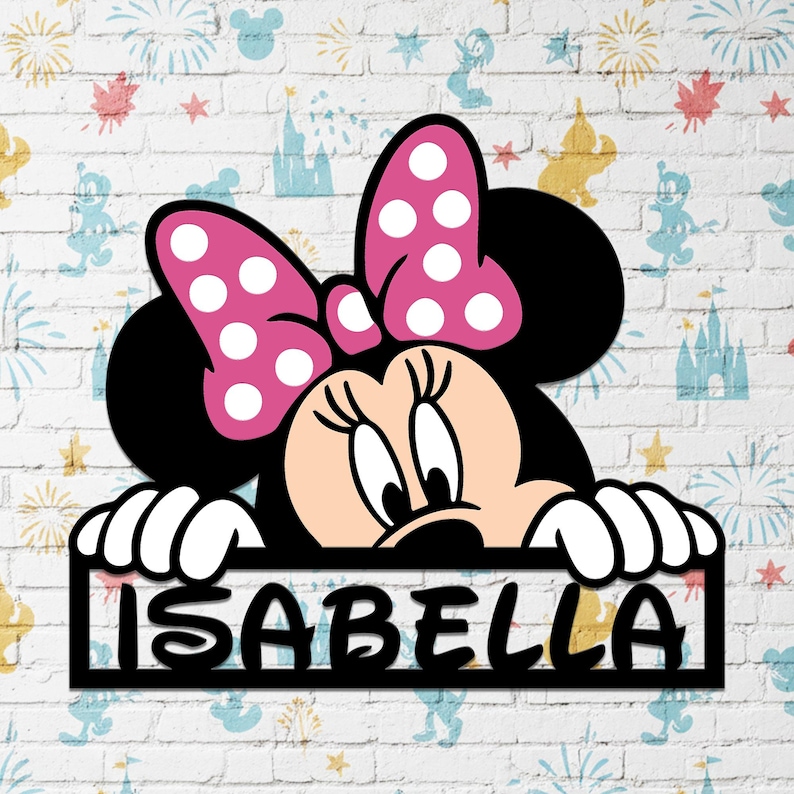 May include: A black Minnie Mouse cutout with a pink bow and white polka dots. The cutout has the name "ISABELLA" in white letters. The background is a white brick wall with Disney-themed illustrations.