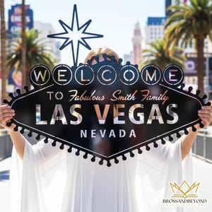 May include: Black metal Las Vegas sign with the text "WELCOME TO Fabulous Smith Family LAS VEGAS NEVADA". The sign has a star at the top and is held up in front of a person. The sign is a decorative item.