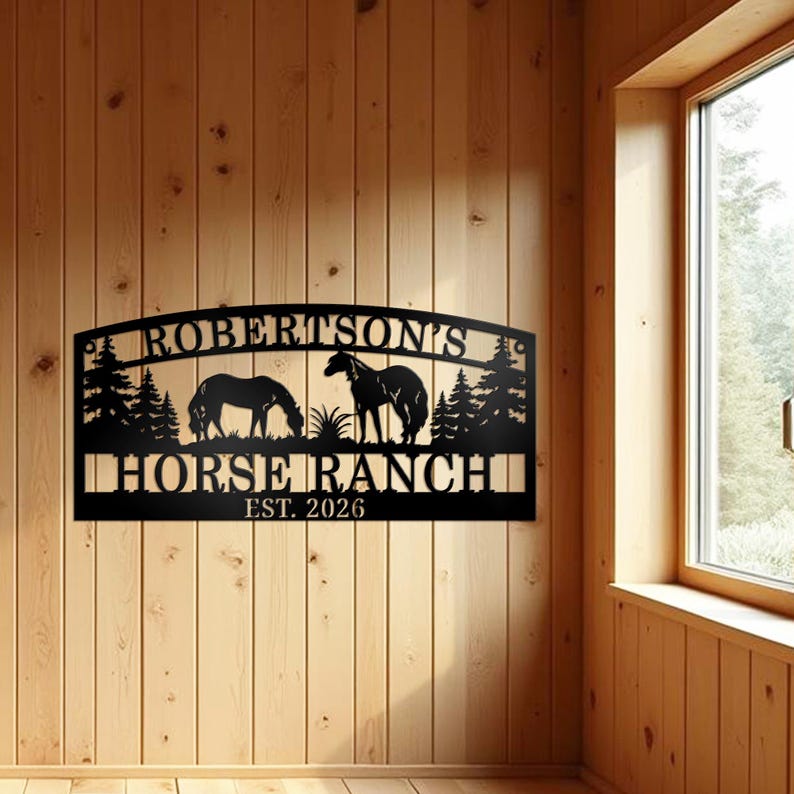 May include: Black metal sign with the text "ROBERTSON'S HORSE RANCH EST. 2026". The sign features silhouettes of two horses, trees, and grass. The sign is mounted on a wooden wall.