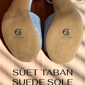 K&ouml;nnte beinhalten: Hellblaue Wildleder-High-Heel-Sandalen mit hellbraunen Sohlen. Die Sohlen tragen das "GELTONY"-Logo. Der Text "S&Uuml;ET TABAN SUEDE SOLE" ist unten im Bild in Schwarz dargestellt.