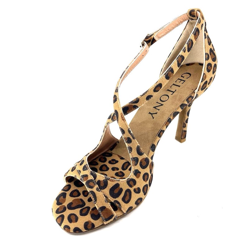 K&ouml;nnte beinhalten: High-Heel-Sandale mit Leopardenmuster. Der offene Schuh hat ein gekreuztes Riemendesign und einen Kn&ouml;chelriemen. Der Absatz ist etwa 10 cm hoch. Der Markenname "GELTONY" ist auf der Innensohle sichtbar.