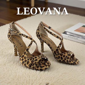 K&ouml;nnte beinhalten: Ein Paar hochhackige Sandalen mit Leopardenmuster. Die Sandalen haben d&uuml;nne Riemen und einen Schnallenverschluss. Der Markenname "GELTONY" ist auf der Innensohle sichtbar. Das Wort "LEOVANA" wird oben in gro&szlig;en wei&szlig;en Buchstaben angezeigt.