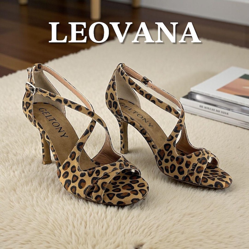 K&ouml;nnte beinhalten: Ein Paar hochhackige Sandalen mit Leopardenmuster. Die Sandalen haben d&uuml;nne Riemen und einen Schnallenverschluss. Der Markenname "GELTONY" ist auf der Innensohle sichtbar. Das Wort "LEOVANA" wird oben in gro&szlig;en wei&szlig;en Buchstaben angezeigt.