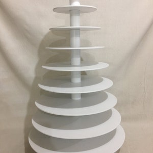 May include: White tiered cake stand with nine circular tiers. The stand is made of white plastic and has a conical shape.