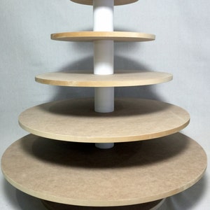 May include: A five-tiered wooden cake stand with white pillars. The stand is made of natural wood and has a rustic look.