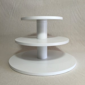 May include: White three-tiered cake stand with round platforms and a white base.