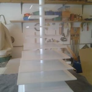 May include: White tiered display stand with multiple shelves. The stand is made of wood and has a simple, modern design.