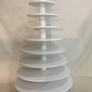 May include: White tiered stand with nine circular shelves. The stand is made of wood and has a white finish.