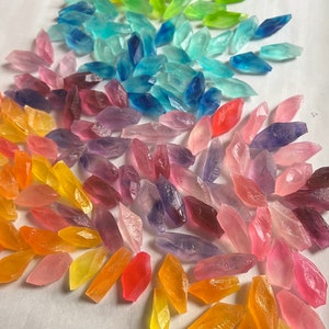 May include: A rainbow assortment of small, clear, faceted glass crystals. The crystals are arranged in a fan shape, with the green crystals at the top and the orange crystals at the bottom.