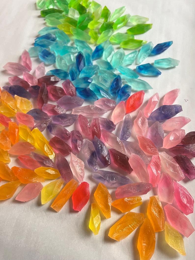 May include: A rainbow assortment of small, clear, faceted glass crystals. The crystals are arranged in a fan shape, with the green crystals at the top and the orange crystals at the bottom.