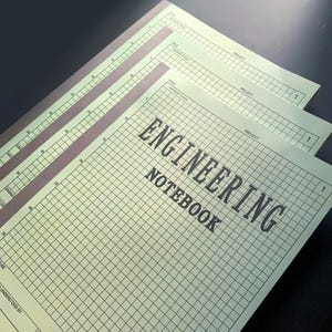 May include: Several engineering notebooks with a grid pattern and the words "ENGINEERING NOTEBOOK" printed on the cover. The notebooks have a light green background with black grid lines and text. The covers have a dark purple border.