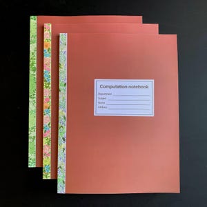 May include: Three computation notebooks with solid terracotta-colored covers and a white rectangular label featuring the text Computation notebook, Department, Subject, Name, and Address. Each notebook has a vertical floral patterned spine.
