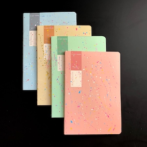 May include: Four notebooks in pastel colors: light blue, yellow, green, and pink. Each notebook has a splatter paint design in various colors. The notebooks have a rectangular label with the text "NOTEBOOK" and "RIGHT PAPER".