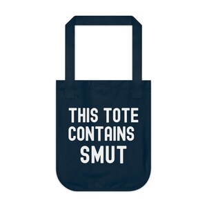 Pode incluir: Saco tote azul marinho com texto branco "THIS TOTE CONTAINS SMUT". O saco tem uma abertura retangular e duas al&ccedil;as. O texto est&aacute; centrado na frente do saco.