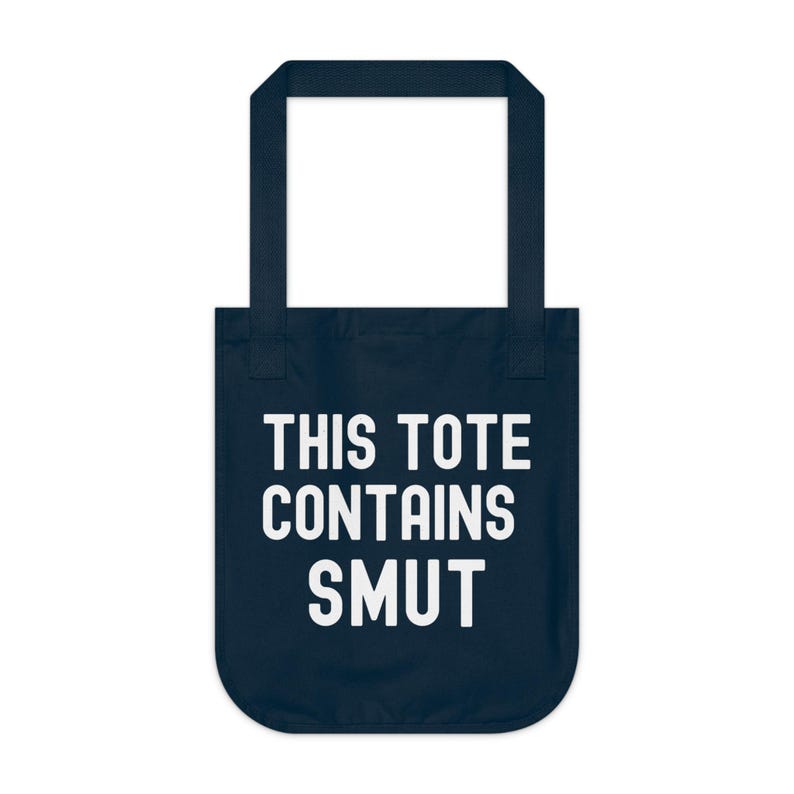 Pode incluir: Saco tote azul marinho com texto branco "THIS TOTE CONTAINS SMUT". O saco tem uma abertura retangular e duas al&ccedil;as. O texto est&aacute; centrado na frente do saco.