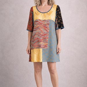 Könnte beinhalten: Ein Patchwork-Kleid mit kurzen Ärmeln und einem Rundhalsausschnitt. Das Kleid hat Stoffbahnen in Gelb, Rot, Blau und Schwarz mit verschiedenen Mustern. Das Model trägt schwarze Absätze.