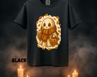 May include: Black t-shirt featuring a cartoon ghost wearing a scarf and holding a pumpkin and a coffee cup. The ghost is surrounded by autumn leaves. The word "BLACK" is printed at the bottom of the shirt.