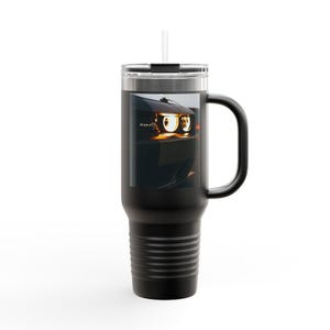 Puede incluir: Vaso de viaje negro con asa y pajita. El vaso presenta una imagen de los faros de un coche. Los faros son de color amarillo brillante y naranja. El vaso tiene una tapa negra y un asa negra.