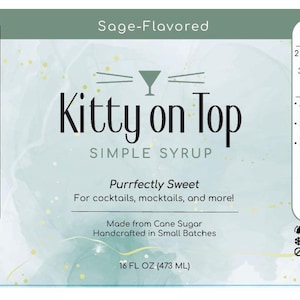 May include: A label for "Kitty on Top" simple syrup, sage-flavoured, with nutrition facts and a "Whiskey Smash" cocktail recipe. The label is white with green accents and features the text "Purrfectly Sweet" for cocktails and mocktails. Contains 473 ml.