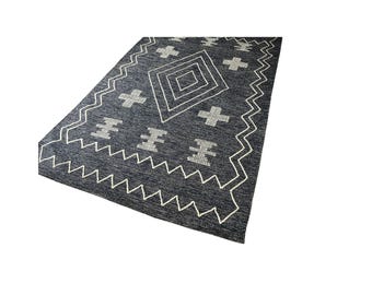Puede incluir: Una alfombra azul oscuro con un diseño geométrico. Presenta una forma de diamante central y patrones de cruces, todos delineados en blanco. El borde tiene un patrón en zigzag. Ideal para el salón.