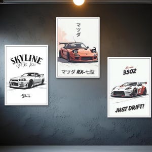 Puede incluir: Tres láminas enmarcadas con ilustraciones de coches deportivos. Las láminas incluyen un Skyline GTR R34 blanco, un Mazda RX-7 rojo y un Nissan 350Z blanco. La lámina del Nissan dice "JUST DRIFT!"