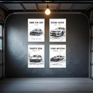 May include: Four framed automotive art prints featuring classic car models: BMW E30 3251, Nissan Silvia S15 2002, Toyota AE86 Trueno 1985, and Ford Mustang Foxbody 1991. Each print includes the car model name, year, and a tagline. The prints are displayed on a textured gray wall.