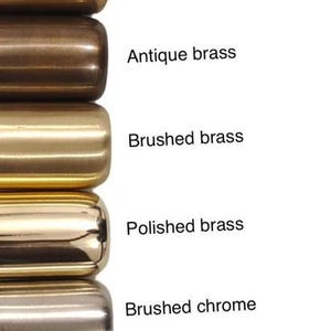 May include: A vertical column of ten cylindrical metal hardware samples with various finishes labeled as Brushed antique brass, Antique black, Blackened brass, Raw brass, Antique brass, Brushed brass, Polished brass, Brushed chrome, Polished chrome, Matte black, and Matte white.