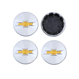 Peut inclure: Quatre enjoliveurs argentés avec le logo Chevrolet doré. Trois enjoliveurs affichent le logo, tandis que le quatrième révèle le dos en plastique noir. Les enjoliveurs sont ronds et ont une finition en métal brossé.