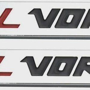 Peut inclure: Deux emblèmes rectangulaires argentés avec le texte "5.3L VORTEC". Le "5.3L" est en rouge et "VORTEC" est en noir. Les emblèmes ont un aspect en relief en trois dimensions.