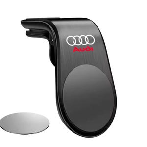 May include: Black car vent phone mount with the Audi logo in white and red. Includes a separate silver metal disc. The mount is designed to attach to a car's air vent and hold a phone securely.