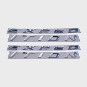 Op de afbeelding: Vier sets verchroomde letters met de tekst "EXPEDITION" worden weergegeven op een lichtgrijze achtergrond. De letters zijn individueel en lijken zelfklevend te zijn, waarschijnlijk voor voertuigaanpassing. De letters hebben een metallic glans.