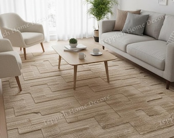 May include: A beige geometric patterned area rug in a living room setting. The rug is placed under a light wood coffee table, two armchairs, and a sofa. The room has white curtains and walls, with a potted plant and decorative pillows.