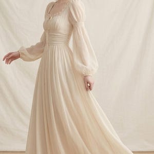 以下が含まれることがあります： 丸いネックラインと長いバルーンスリーブが特徴の、アイボリー色のロングドレス。 ドレスは、ウエストが絞られており、繊細なレースのディテールが施されています。 生地は優雅にドレープし、ロマンチックで幻想的な外観を作り出しています。特別な機会に最適です。