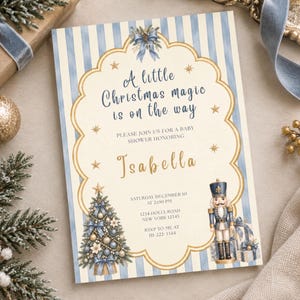 Könnte beinhalten: Eine rechteckige Einladungskarte für eine Babyparty mit blau-weiß gestreiftem Hintergrund und einem cremefarbenen, geschwungenen Rahmen. Der Text lautet: A little Christmas magic is on the way, please join us for a baby shower honoring Isabella, Saturday December 10 at 2:00 PM, 1234 Holly Road, New York 12345, RSVP to me at 111-222-3344. Das Design zeigt einen geschmückten Weihnachtsbaum und einen Nussknacker.