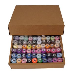 May include: A brown cardboard box containing a large collection of sewing thread spools in a wide variety of colors. The spools are arranged in neat rows and are individually wrapped in clear plastic film to keep them organized and protected.