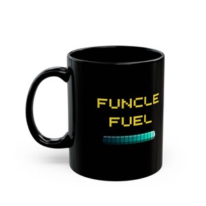 May include: Black ceramic mug with the text "FUNCLE FUEL" in yellow pixelated font, and a teal progress bar graphic. The mug has a curved handle and a glossy finish.