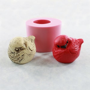 May include: Two small bird figurines, one red and one beige, with a pink silicone mold for making similar figurines.