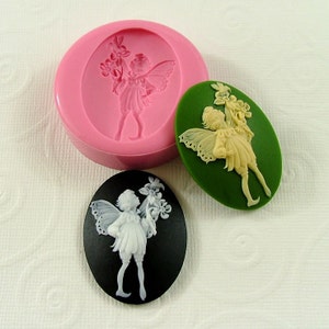 May include: Three silicone molds for making resin or polymer clay charms. The molds are oval shaped and feature a fairy design with wings and flowers. The molds are pink, green, and black.