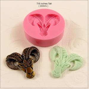 May include: A pink silicone mold for making a ram head pendant. The mold is 7/8 inches tall (22mm). Two finished pendants are shown, one in bronze and one in green.