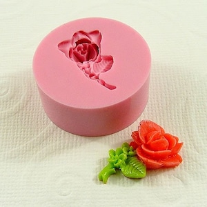 May include: A pink silicone mold for making a single rose flower. The mold is shown with a finished rose made from polymer clay, with a pink rose and green leaves.
