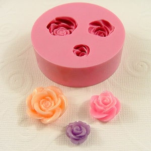May include: Pink silicone mold with three rose-shaped cavities. Three finished roses are shown in pink, orange, and purple.