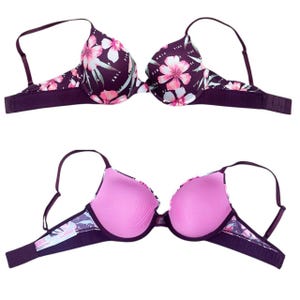 Puede incluir: Sujetador con estampado floral en tono morado oscuro, con flores rosas y blancas y hojas verdes. El sujetador tiene tirantes ajustables y cierre de corchete. El interior es de color rosa liso.