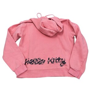 May include: A pink hooded sweatshirt with long sleeves. The back of the sweatshirt features the words "Hello Kitty" in black script. The hoodie has a drawstring and a kangaroo pocket.