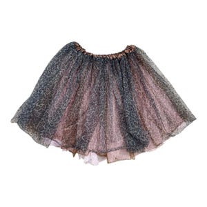 May include: A layered tutu skirt with a leopard print pattern in shades of gray and pink. The skirt has a gathered waistband and a flowing, airy design. The skirt is designed for children.